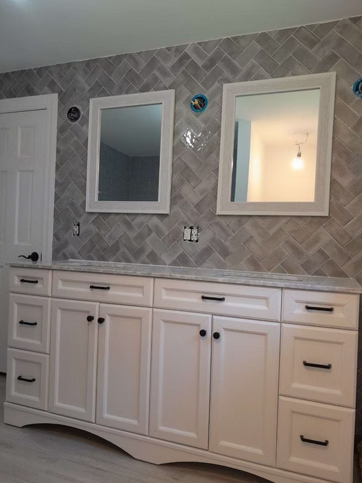 A bathroom with white cabinets and two mirrors on the wall.