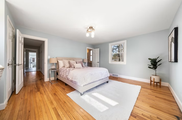 A bedroom with a large bed and hardwood floors.