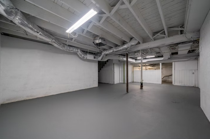 An empty basement with a gray floor and white walls.