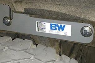 Gray B&W Tow and Stow bracket mounted near a truck tire.