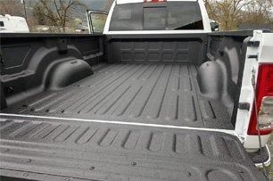 White pickup truck bed with black bedliner, empty.