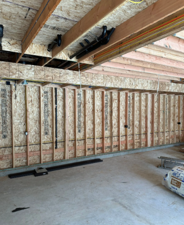 Basement under construction with exposed wooden beams, insulation, and unfinished wall framing