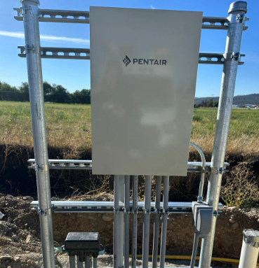 Pentair electrical control panel mounted on metal frame in a grassy outdoor utility site