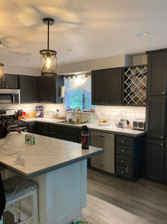 Modern kitchen with dark cabinets, white island, hanging pendant light, and wine rack