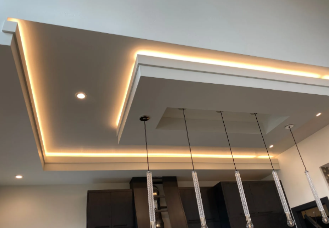 Modern ceiling with recessed lighting and warm LED strip accents above pendant lights