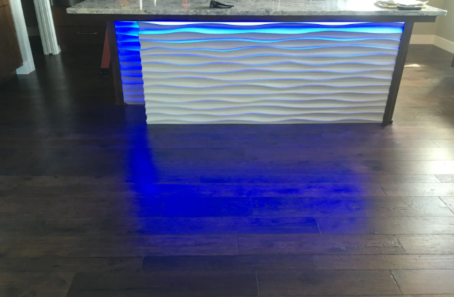 Modern white reception desk with blue underlighting on a dark wood floor