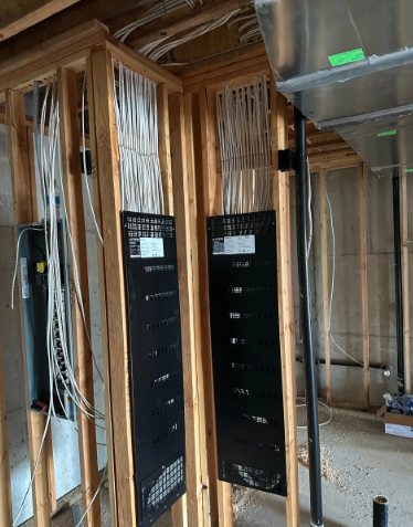 Partially framed room with black electrical panels and exposed wiring in a construction site