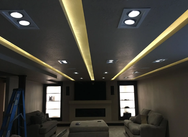 Modern living room with recessed ceiling lights, sofa, and TV fireplace wall