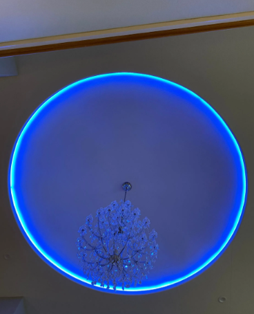 Ceiling with a glowing blue circular LED light above a chandelier.