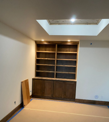 Empty room with built-in wooden shelves, skylight, and a panel leaning against the wall