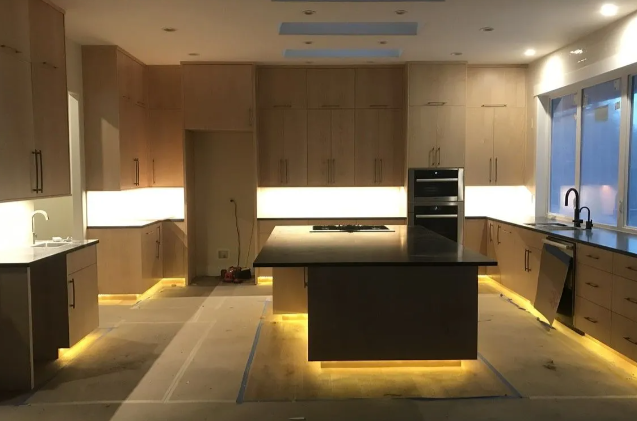 Modern kitchen with warm wood cabinetry, central island, and under-cabinet lighting