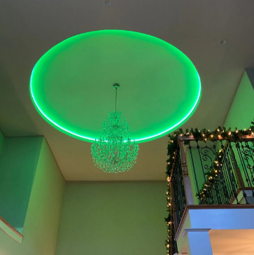 Ceiling with green LED ring light and crystal chandelier above a decorated balcony interior