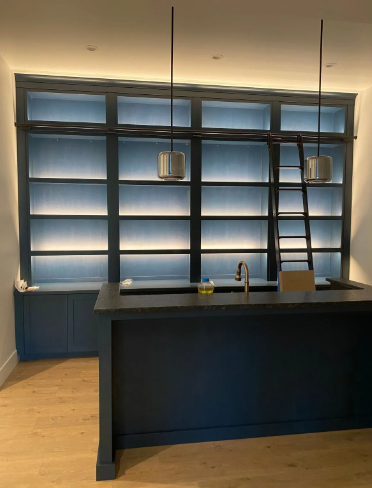Modern kitchen with dark blue island, pendant lights, and frosted window wall