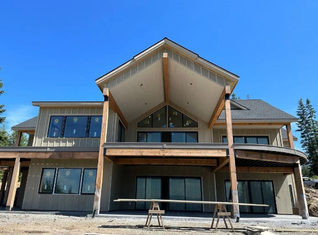 Large modern house with a steep gabled roof and wide windows under a clear blue sky