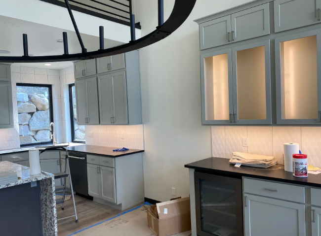 Modern kitchen with gray cabinets, black countertops, and a spiral staircase overhead