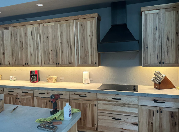 Modern kitchen with wooden cabinets, black range hood, and a countertop island with greens on it