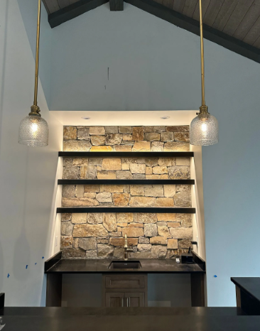 Stone fireplace wall with black shelves and pendant lights in a modern room