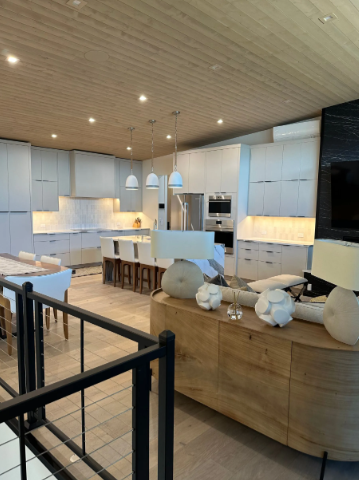 Modern open-plan kitchen and living area with light cabinets, wood accents, and a curved sofa.