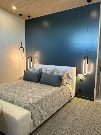 Modern bedroom with a blue accent wall, queen bed, pendant lights, and patterned bedding
