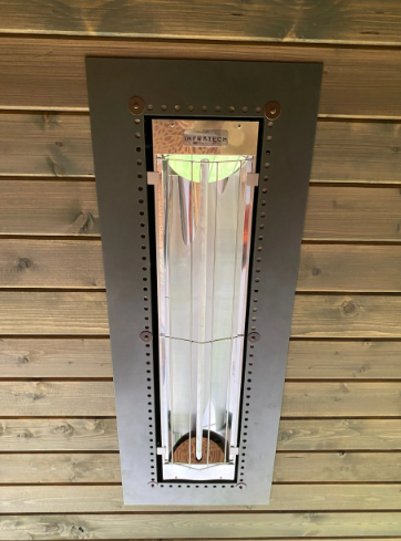 Wall-mounted silver heater in a black-framed panel against wood planks