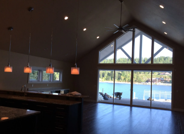 Modern lodge interior with hanging lights and large windows overlooking a blue lake