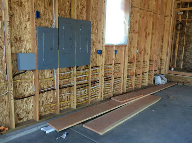 Unfinished room with exposed wall studs, electrical panels, and boards on the floor
