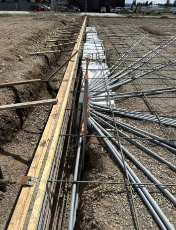 Construction site with steel rebar and formwork trench beside dirt ground