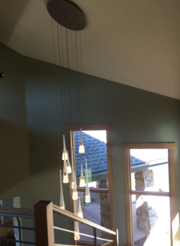 Interior stairwell with green walls, hanging pendant lights, and windows letting in daylight
