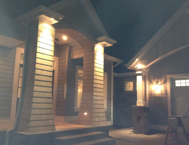 Lit porch entrance of a house at night with columns and warm lights