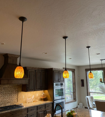 Modern kitchen with dark cabinets, pendant lights, and a windowed dining nook