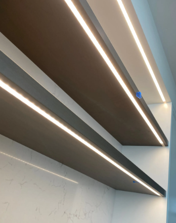 Modern interior ceiling with long recessed LED strip lights and dark wood panels