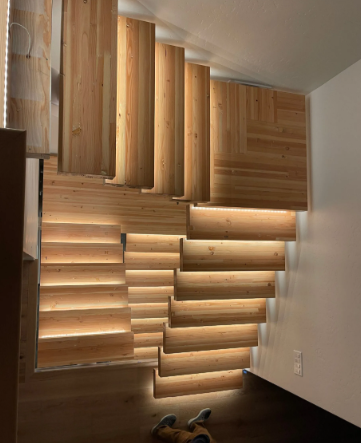 Wooden slat wall installation in a room corner with warm light and dark floor