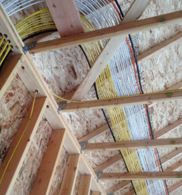 Wooden roof trusses and exposed insulation with wire mesh on a slanted ceiling construction site