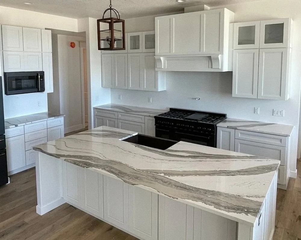 White kitchen with marble countertops, black range, and island.