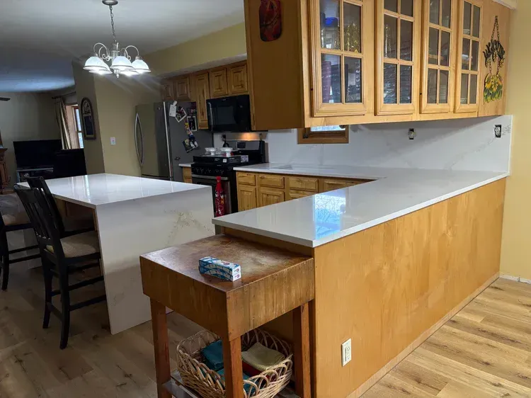 Kitchen with light countertops, wood cabinets, and an island with seating.