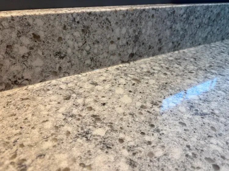 Close-up view of a speckled white and gray countertop with a built-up edge.