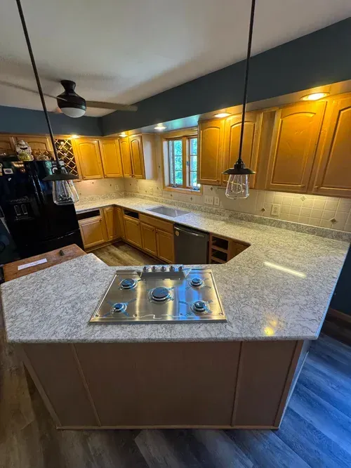 Kitchen with light wood cabinets, gray countertops, and a gas cooktop.