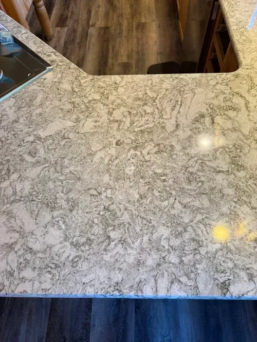 Overhead view of a kitchen countertop with gray and white veining, wood floor below.
