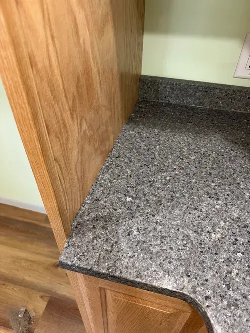 Gray speckled countertop next to a light brown cabinet in a kitchen setting.