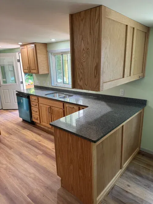 Kitchen with wood cabinets, dark countertop, and light green walls.