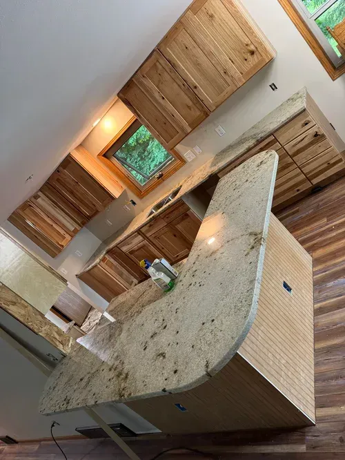 Kitchen with wooden cabinets and granite countertops. Island with rounded edge.