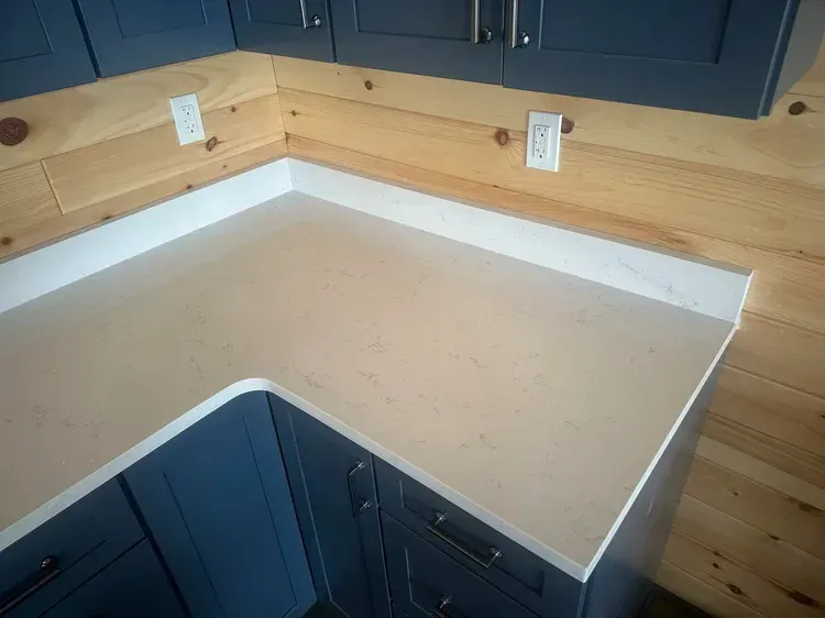 Kitchen corner with light countertop, blue cabinets, and wood paneling on the walls.