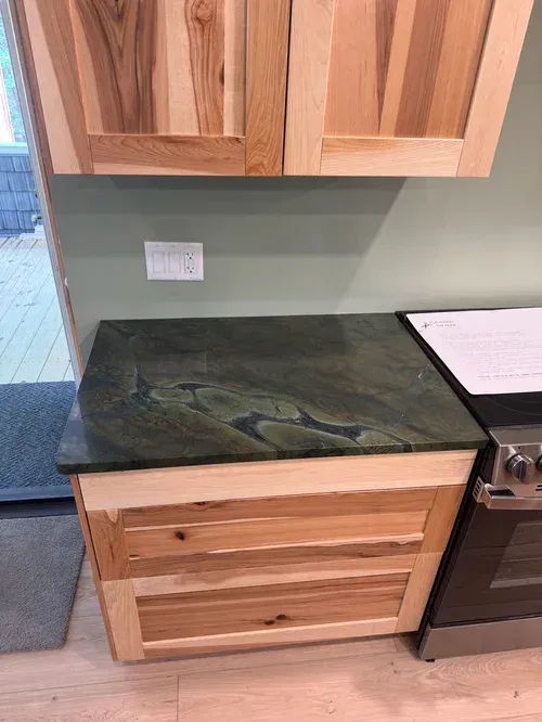 Wooden kitchen cabinets with a dark green countertop.