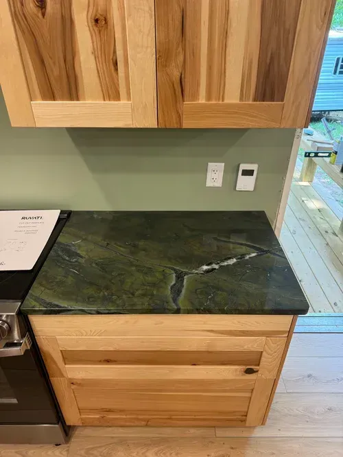 Kitchen cabinetry with green countertop and wooden cabinets.