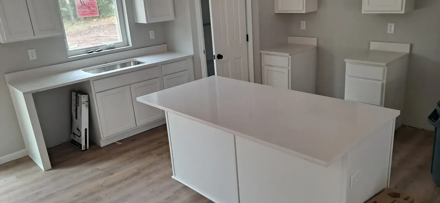 White kitchen with an island, countertops, cabinets, and a window.