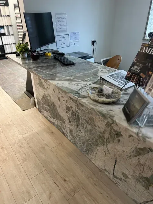 Marble countertop reception desk in an office. Computer, keyboard, and brochures are visible.