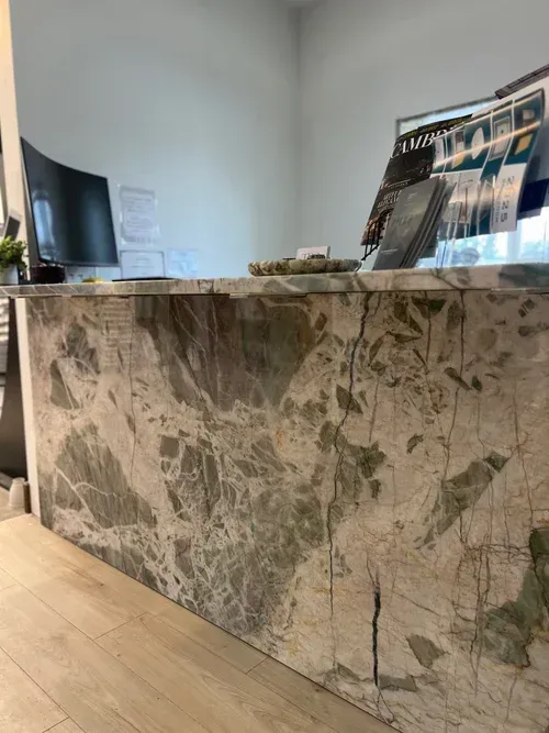 Reception desk with green marble facade and brochures.