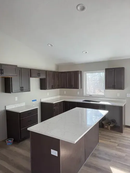 Modern kitchen with dark brown cabinets, white countertops, and an island.