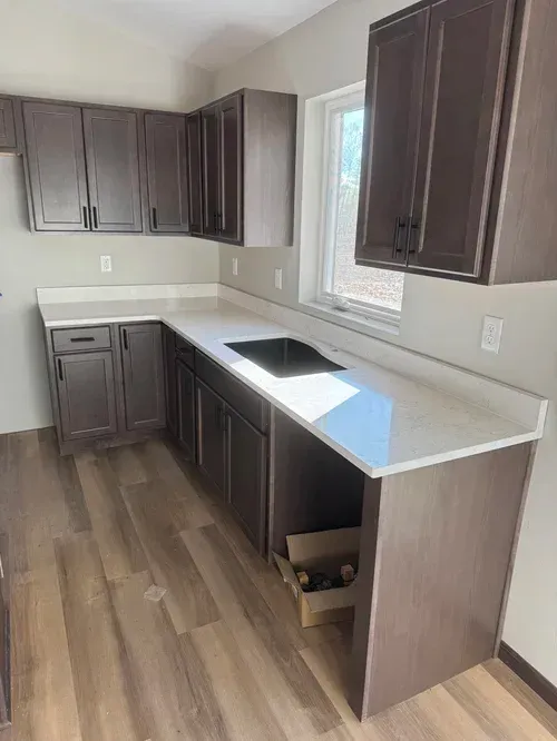 Kitchen with dark brown cabinets, white countertops, a cooktop, and a window.