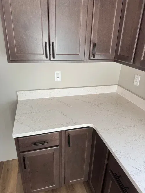 Kitchen corner with brown cabinets, light countertops, and beige walls.